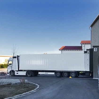 Camion con semirimorchio bianco davanti a un magazzino